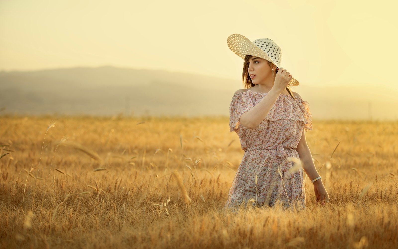 A woman in a straw hat standing in a sunlit field
